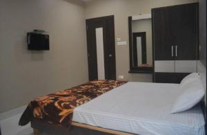 a bedroom with a bed and a tv on the wall at Premium hotel near Nagoa Beach in Diu