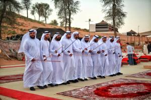 un grupo de hombres con uniformes blancos parados en una fila en Bedouin Oasis Desert Camp- Ras Al Khaimah, en Ras al Khaimah