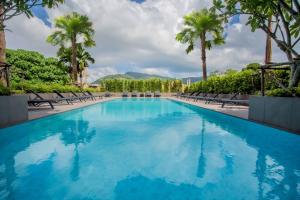 a large pool with chairs and palm trees at NOON Village - Tower 2&3 in Chalong 