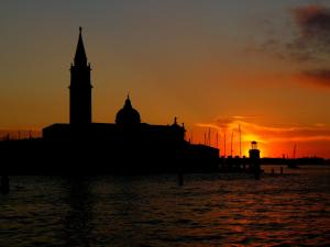 a silhouette of a building with a clock tower at sunset at Porta da mar in Venice
