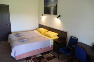 niewielka sypialnia z łóżkiem i niebieskim krzesłem w obiekcie Vila Romnesa w mieście Ignalino