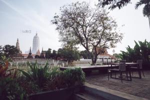 a table and chairs in a park with a view of temples at iuDia Hotel in Phra Nakhon Si Ayutthaya