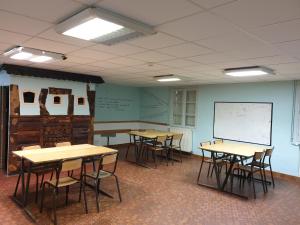 a classroom with tables and chairs and a whiteboard at Peyranère in Urdos