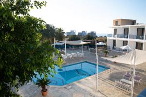 a pool with chairs and umbrellas next to a building at West End Hotel in Peyia