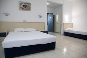 a bedroom with a large white bed and two at West End Hotel in Peyia