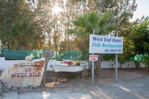 a sign that says west end hotel fish restaurant and a boat at West End Hotel in Peyia