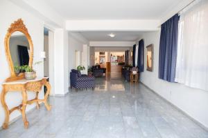 a living room with a mirror and a table and chairs at West End Hotel in Peyia