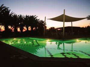 a swimming pool at sunset with an umbrella at West End Hotel in Peyia