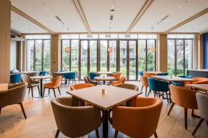 Un restaurante con mesas, sillas y ventanas. en Holiday Inn Express Guizhou Qinglong by IHG, en Qinglong