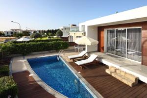 a swimming pool on a deck next to a house at Paradise Cove Luxurious Beach Villas in Paphos