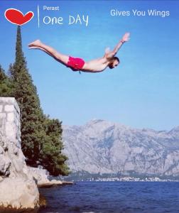 a woman doing a flip in the air over a body of water at Apartment Mediterraneo Blue Sky in Perast