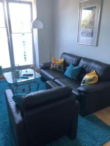 un soggiorno con divani in pelle nera e tavolo in vetro di Apartment mit Parkblick a Tönisvorst