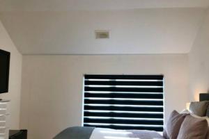 een slaapkamer met een raam in een witte muur bij Spacious & Luxurious 1 bed House in Thamesmead in Thamesmead
