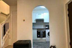 an archway leading into a kitchen with a washer and dryer at Spacious & Luxurious 1 bed House in Thamesmead in Thamesmead