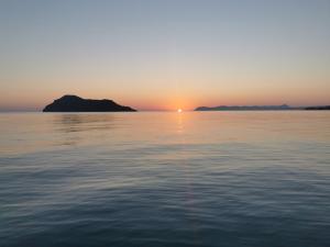 una puesta de sol sobre el agua con islas en la distancia en Kato Stalos Mare, en Stalós