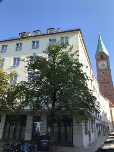 ein Gebäude mit einem Uhrturm und einem Baum in der Unterkunft Hotel Der Tannenbaum in München