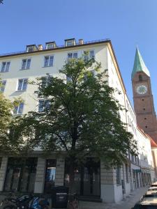 a building with a clock tower and a tree at Hotel Der Tannenbaum in Munich