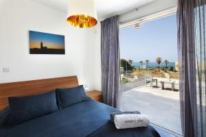 a bedroom with a blue bed and a large window at Paradise Cove Luxurious Beach Villas in Paphos