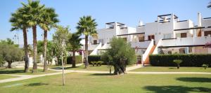 un gran edificio blanco con palmeras en un parque en 3 Bed Apartment Condado de Alhama Golf Resort, en Alhama de Murcia