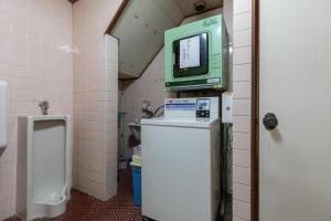 a bathroom with a tv on top of a urinal at Tabist Futaba Ryokan Tatsuno in Tatsuno