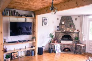 a living room with a stone fireplace and a tv at La Ferma Nagy in Vişeu de Sus