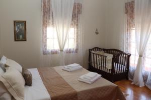 a bedroom with a bed and a crib and windows at Meteoron Guesthouse in Kalabaka