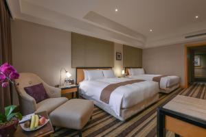 a hotel room with two beds and a chair at THE LEES Hotel in Kaohsiung