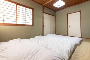 a large white bed in a room with a window at Tabist Futaba Ryokan Tatsuno in Tatsuno