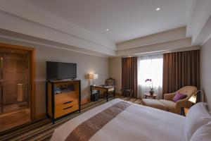 a hotel room with a bed and a flat screen tv at THE LEES Hotel in Kaohsiung