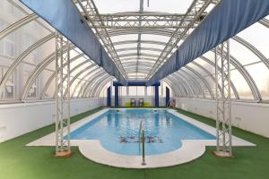 une grande piscine intérieure avec un plafond en verre dans l'établissement Vértice Sevilla, à Séville