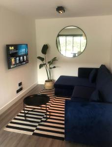 sala de estar con sofá azul y espejo redondo en Paradise Garage, en Hilvarenbeek