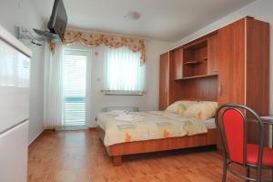 een slaapkamer met een bed en een tafel en stoelen bij Apartmani Vila Caska in Novalja