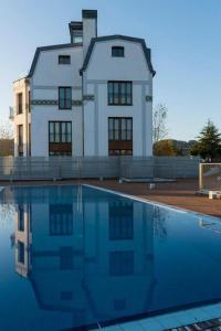 Un gran edificio blanco con una piscina enfrente. en Jaizkibel by Basquelidays, en Hondarribia