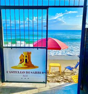 a view of a beach with an umbrella and a sign at Castello di Sabbia in Trabia