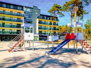a playground in the sand in front of a building at Plaża Resort in Łeba