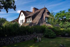 a thatched house with a stone wall in front of it at Ferienwohnung am Tipkenhoog 16 in Keitum