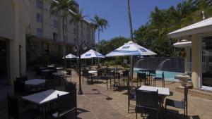 um grupo de mesas e cadeiras com guarda-sóis ao lado de uma piscina em The Riverside Hotel em Durban