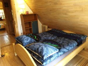 a bed in a wooden room with pillows on it at Błękitny Domek - Tleń - Bory Tucholskie in Tleń