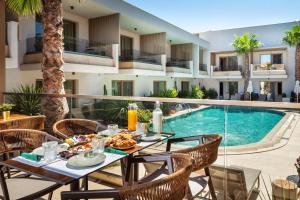 an outdoor patio with a table and chairs next to a swimming pool at Pefki Deluxe Residences - Adults Only 16plus in Pefkochori