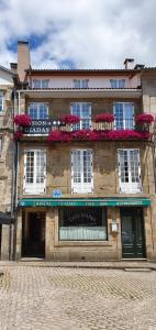 een oud gebouw met bloembakken op de ramen bij Hostal Giadás in Santiago de Compostela