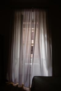 a bedroom window with white curtains and a bed at La Girandola Bed & Breakfast in Rome
