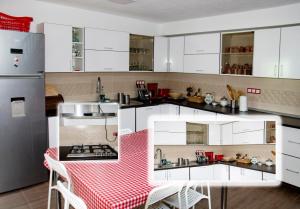 a kitchen with white cabinets and a red and white checkered table at Vila Ozon 90 in Colibiţa