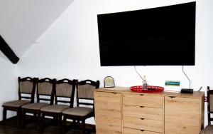 a living room with a television on a dresser with chairs at Vila Ozon 90 in Colibiţa