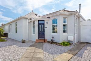 a white house with a blue door at Seafield House - Donnini Apartments in Ayr