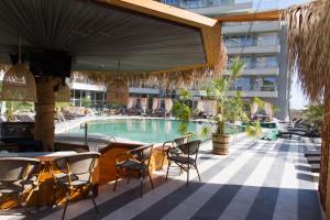 a swimming pool with chairs and a table and a building at Apart Allure Dobi in Primorsko