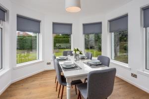 a dining room with a table and chairs and windows at Seafield House - Donnini Apartments in Ayr