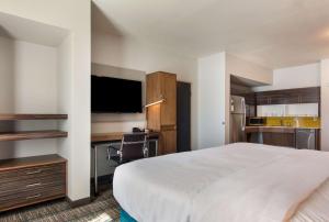 ein Hotelzimmer mit einem Bett, einem Schreibtisch und einem TV in der Unterkunft MainStay Suites East Camden in Camden