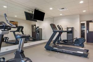 un gimnasio con varias máquinas de correr y TV de pantalla plana en MainStay Suites East Camden, en Camden