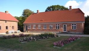 ein Backsteinhaus mit rotem Dach und einem Hof mit Blumen in der Unterkunft Bed & Breakfast Tistrup in Tistrup