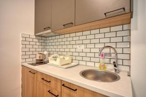 a kitchen with a sink and a white tiled wall at Trsteno Beach Apartments in Budva